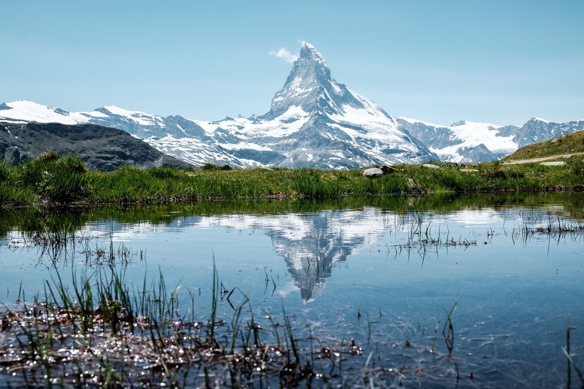 Image shows an alpine mountain covered in ice above a lake