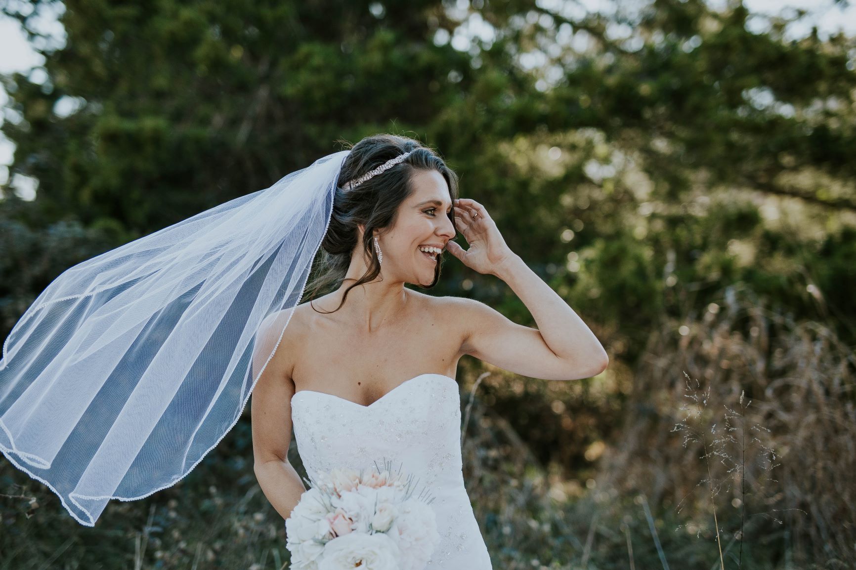 Bride laughing as her veil blows